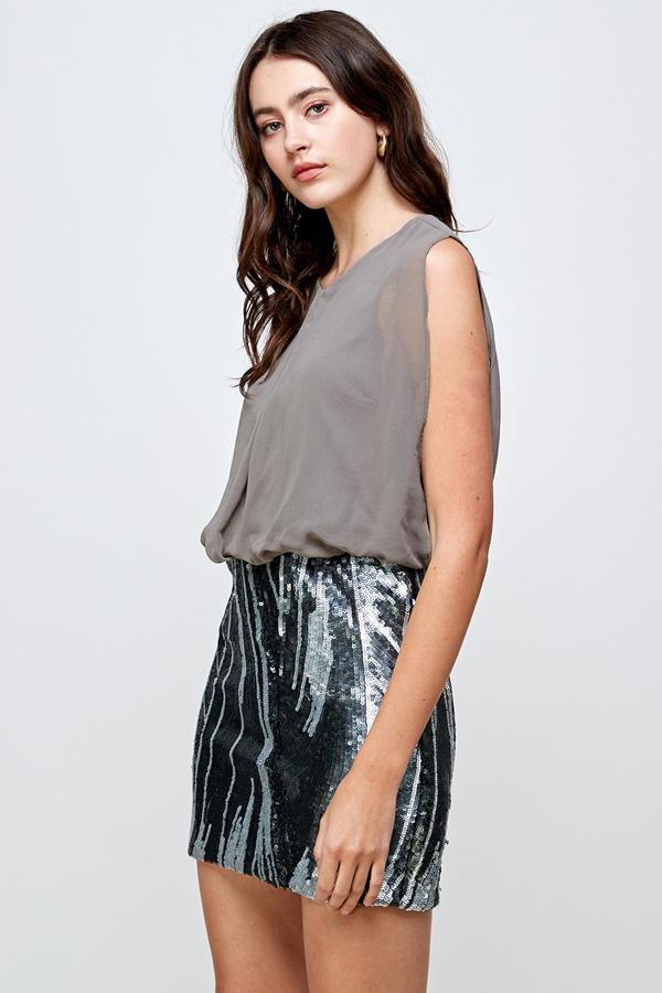 Falda de lentejuelas con vestido blusón sin mangas: un look de fiesta glamuroso
